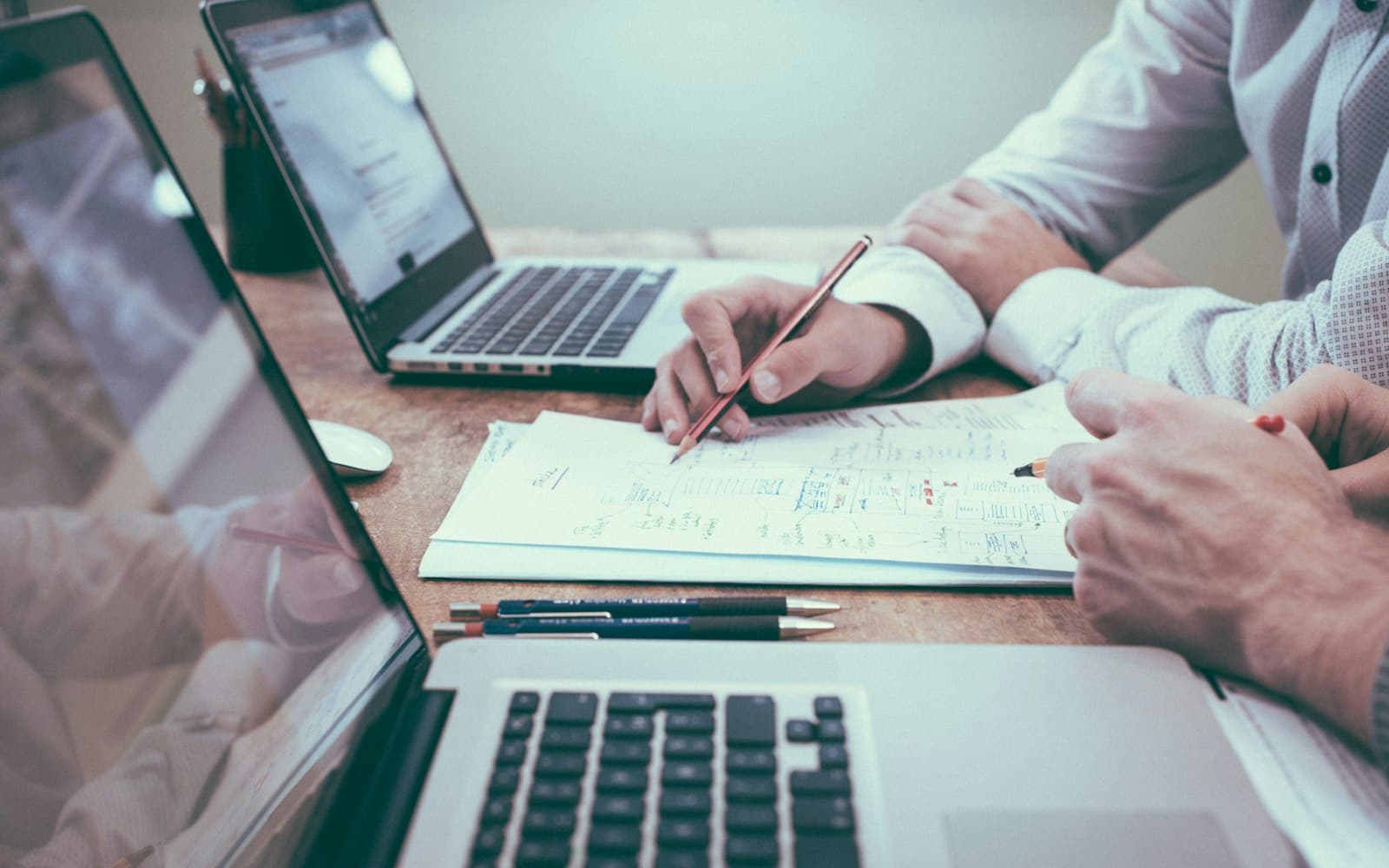 Duas pessoas revisando números com notebook e calculadora sobre a mesa